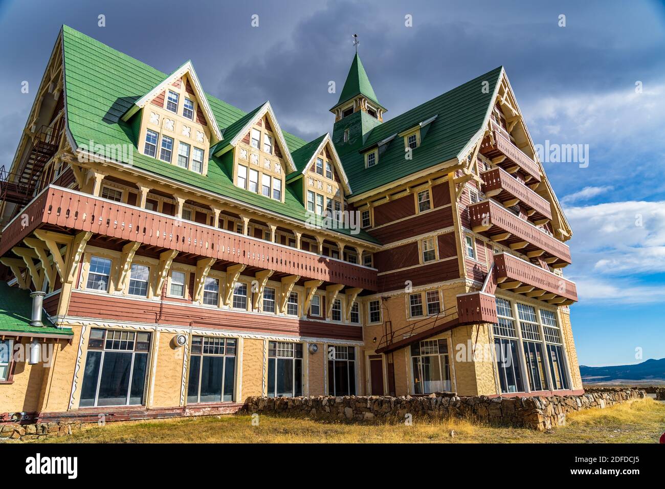 Prince of Wales Hotel in autunno giorno di sole mattina. Cielo blu, nuvole bianche sulle montagne sullo sfondo. Punti di riferimento nel parco nazionale dei laghi di Waterton Foto Stock