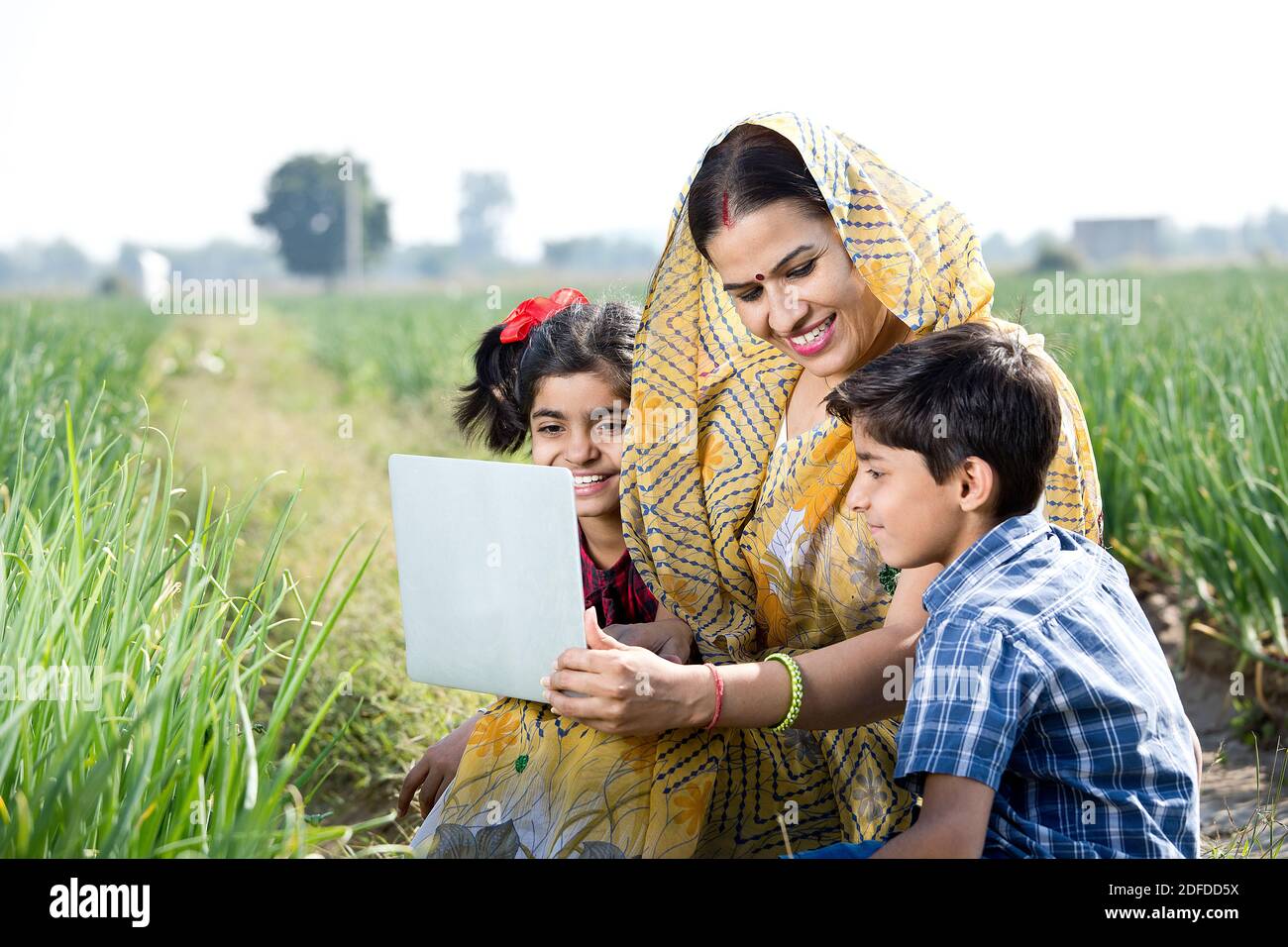 Madre con bambini che usano il laptop sul campo agricolo Foto Stock