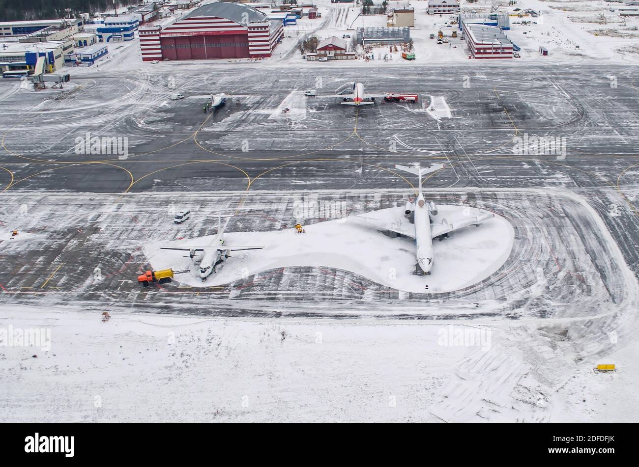 Parcheggio per l'aeroporto e la pista invernale, vista da un'altezza a un paesaggio innevato Foto Stock