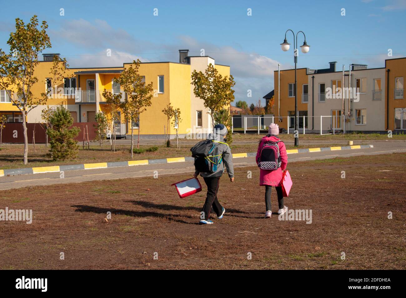 Due bambini tornano a casa dopo la scuola in una giornata di sole Foto Stock