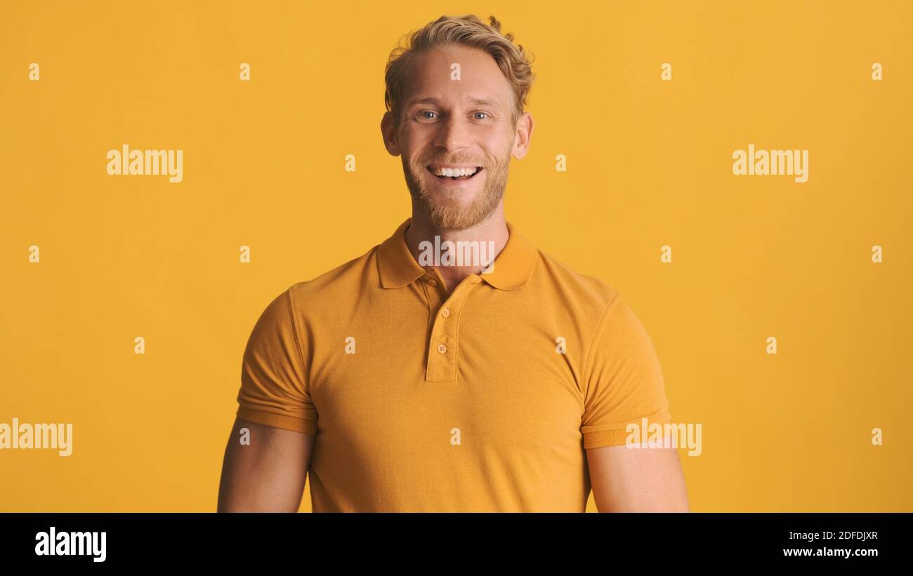 Giovane uomo sorridente con bearded vestito in abito casual che guarda felice sulla fotocamera su sfondo colorato Foto Stock