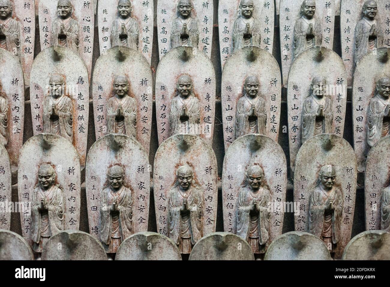 Vista in primo piano frontale orizzontale delle statuette di Buddha in pietra disposte in file nel tempio buddista di Daisho-in, Mt Misen, Miyajima, Giappone Foto Stock