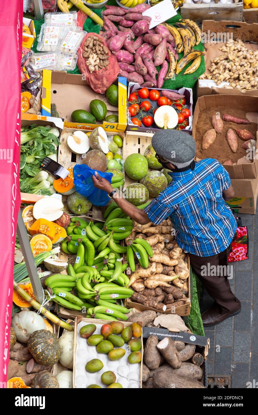 Vista dall'alto di un uomo che acquista prodotti in una bancarella di strada a Brixton Market, Electric Avenue, Brixton, Londra Foto Stock