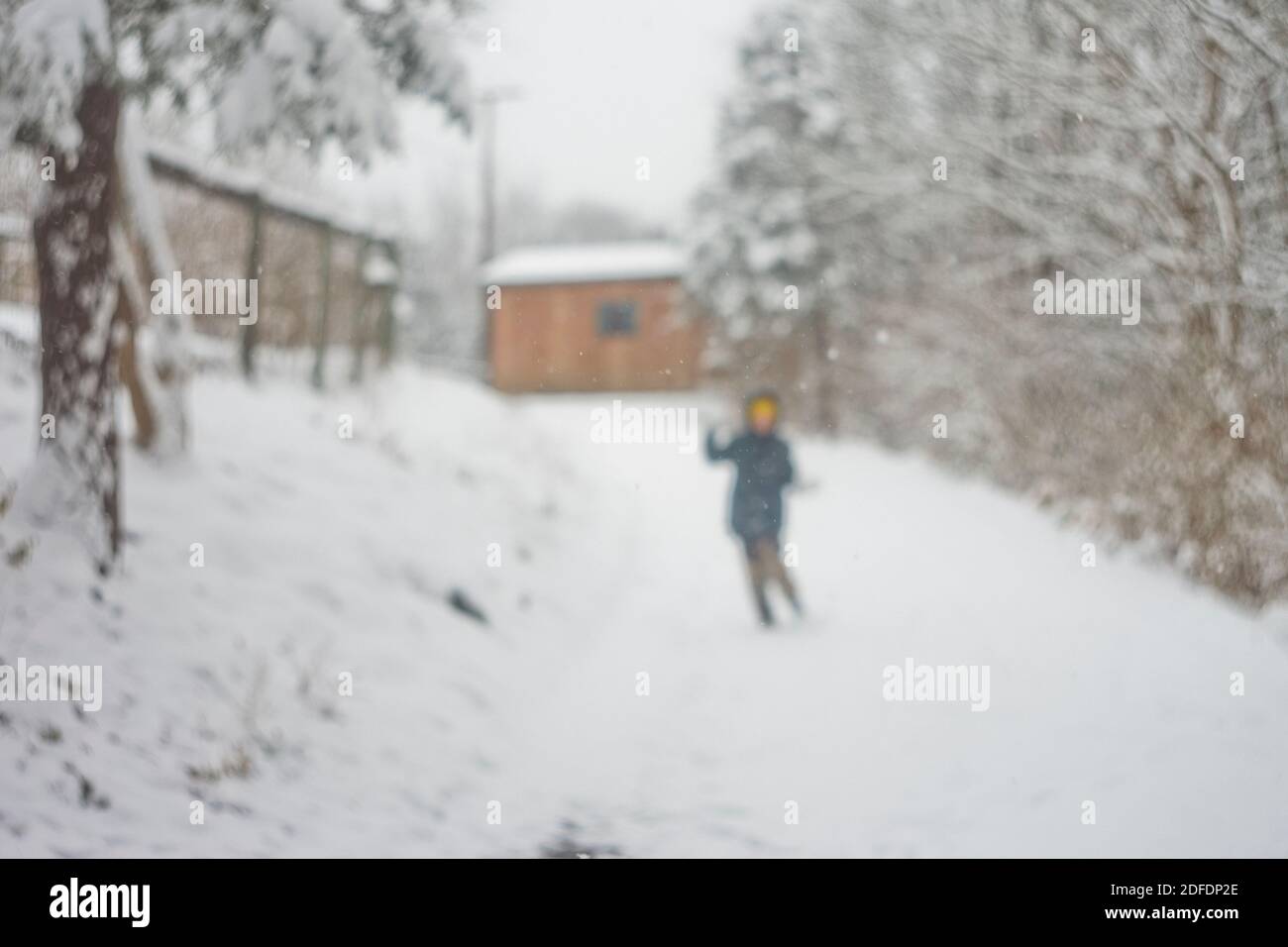 il bambino arroccato corre lungo una collina innevata Foto Stock