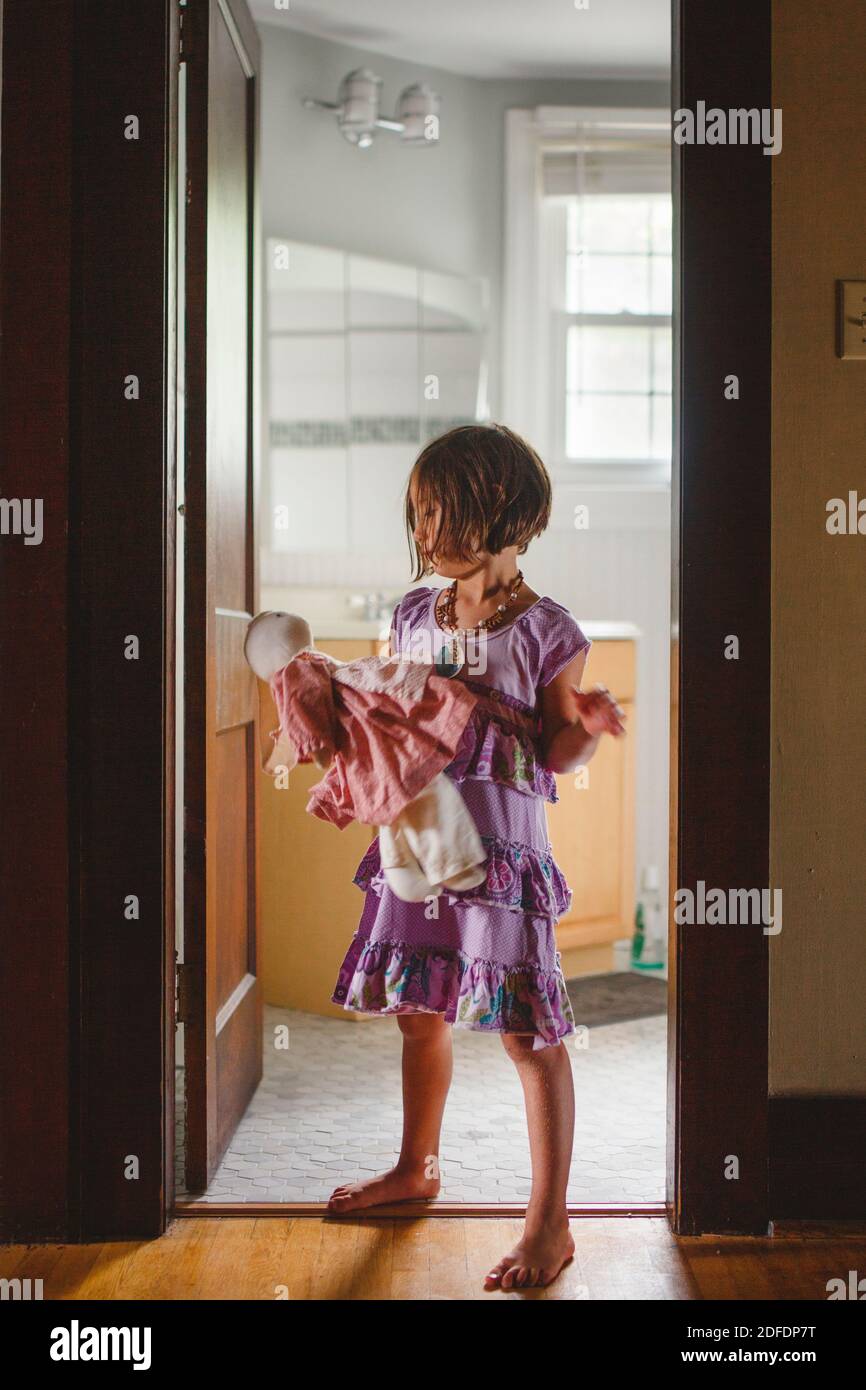 Un bambino a piedi nudi si alza da solo nella porta che tiene un farcito animale Foto Stock