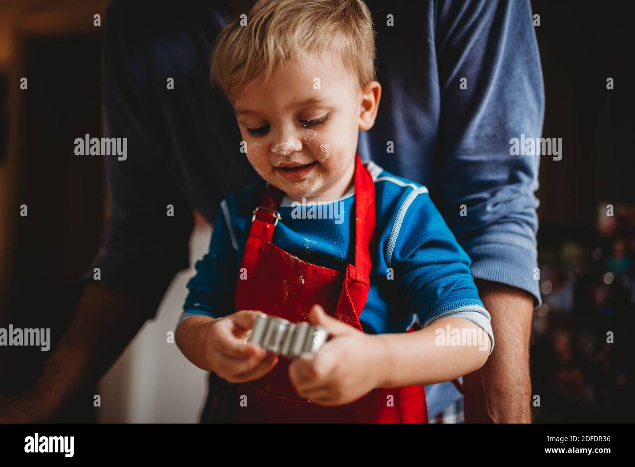 Adorabile ragazzo che cuoce i biscotti natalizi con la faccia piena di farina Foto Stock