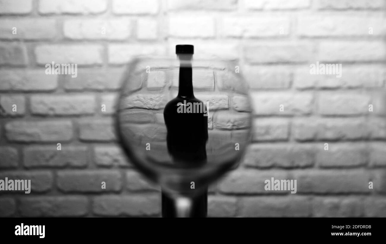 Bicchiere di vino vuoto con una bottiglia di vino su un fondo di mattoni bianchi. Foto Stock