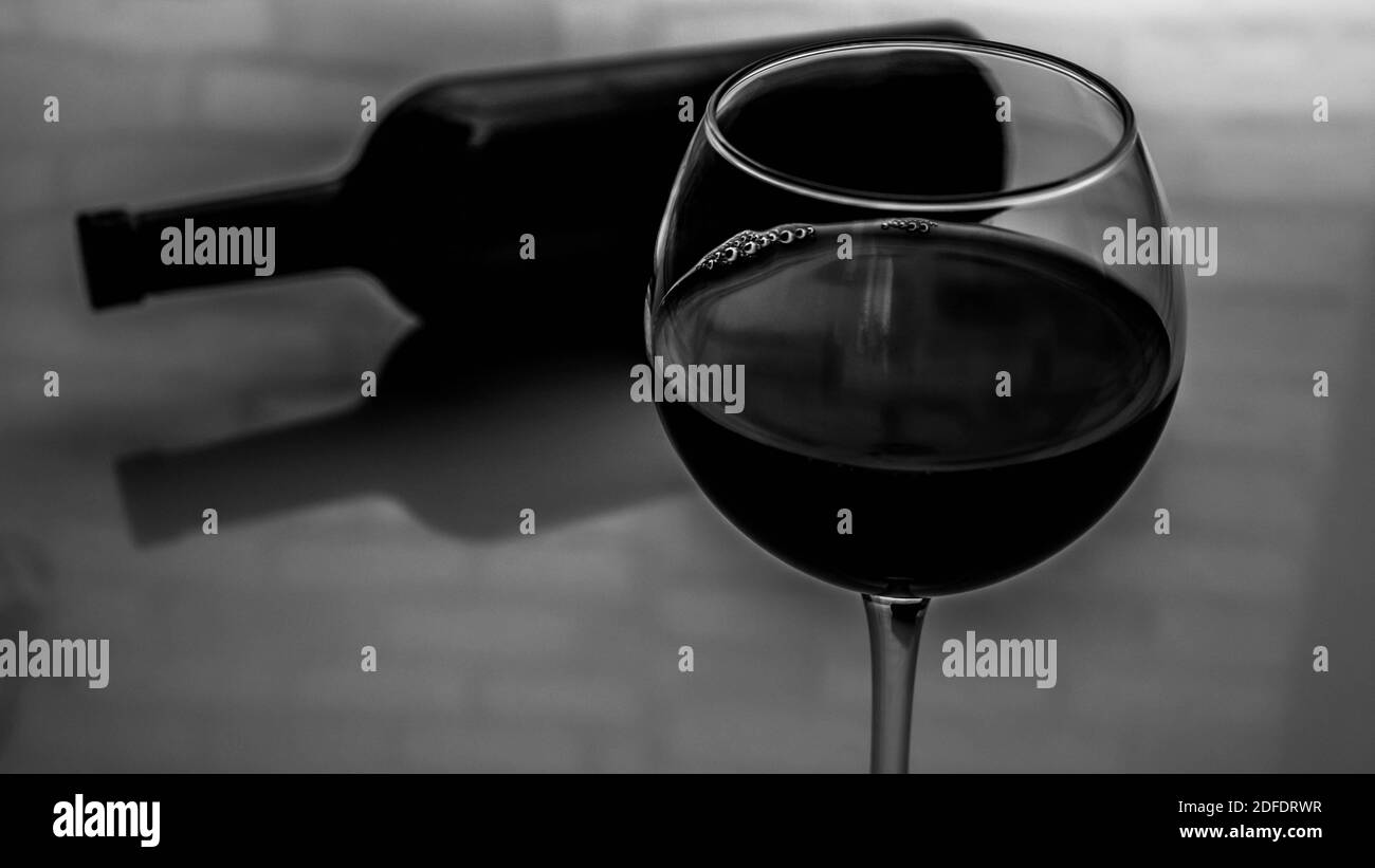 Un bicchiere di vino rosso con una bottiglia di vino. Immagine in bianco e nero del vino in un bicchiere Foto Stock
