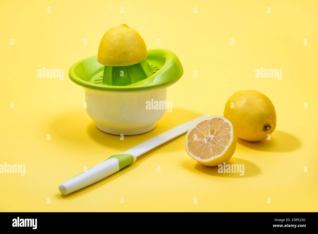 Spremitura del limone su una centrifuga manuale portatile per agrumi colorata Sfondo giallo Foto Stock