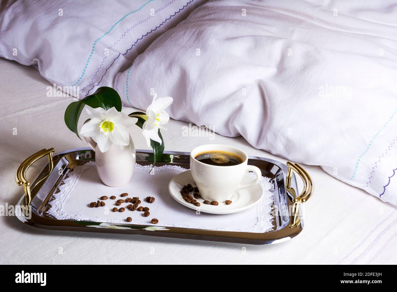 Caffè del mattino a letto su un elegante vassoio d'argento tazza di caffè su squisito tovagliolo ricamato come miglior concetto di servizio alberghiero. Foto Stock