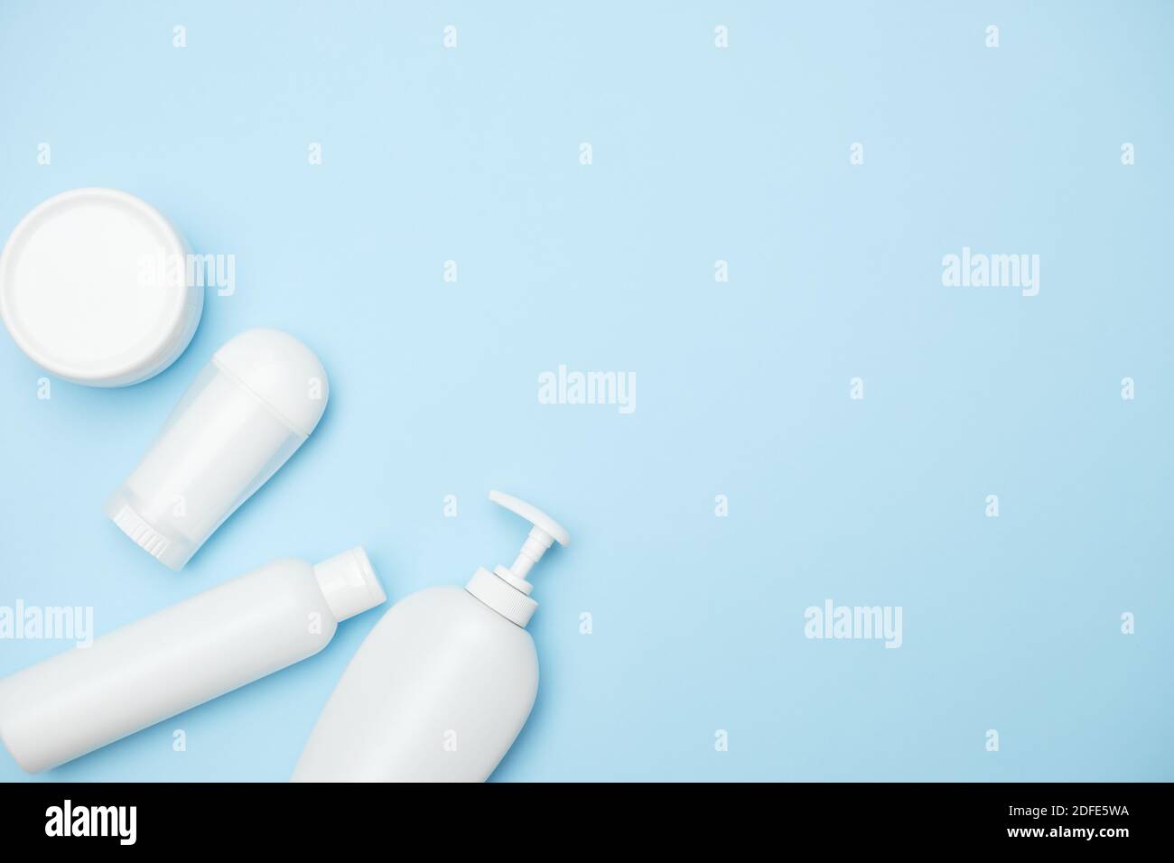 vasetti bianchi per prodotti per l'igiene personale su sfondo blu, spazio per la copia, vista dall'alto Foto Stock