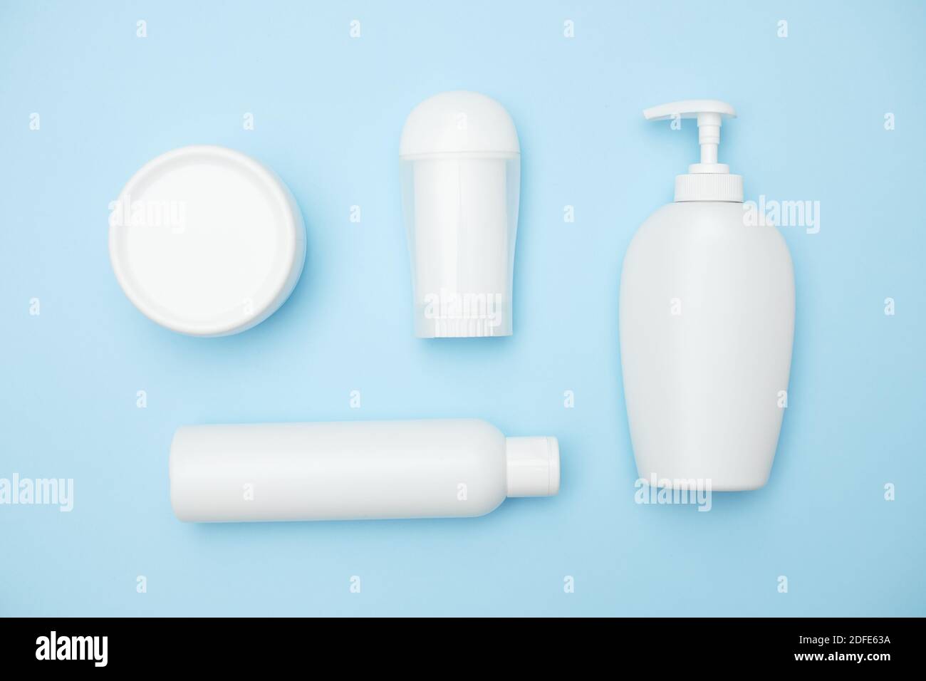 vasetti bianchi per prodotti per l'igiene personale su sfondo blu, spazio per la copia, vista dall'alto Foto Stock