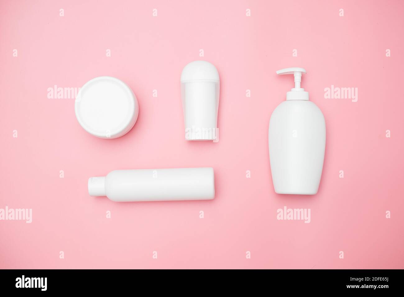 vasetti bianchi per prodotti per l'igiene personale su sfondo rosa, spazio per la copia, vista dall'alto Foto Stock