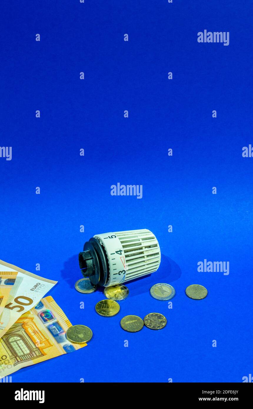 Banconote, monete e un termostato di fronte ad uno sfondo blu, concetto di costi accessori di un appartamento Foto Stock