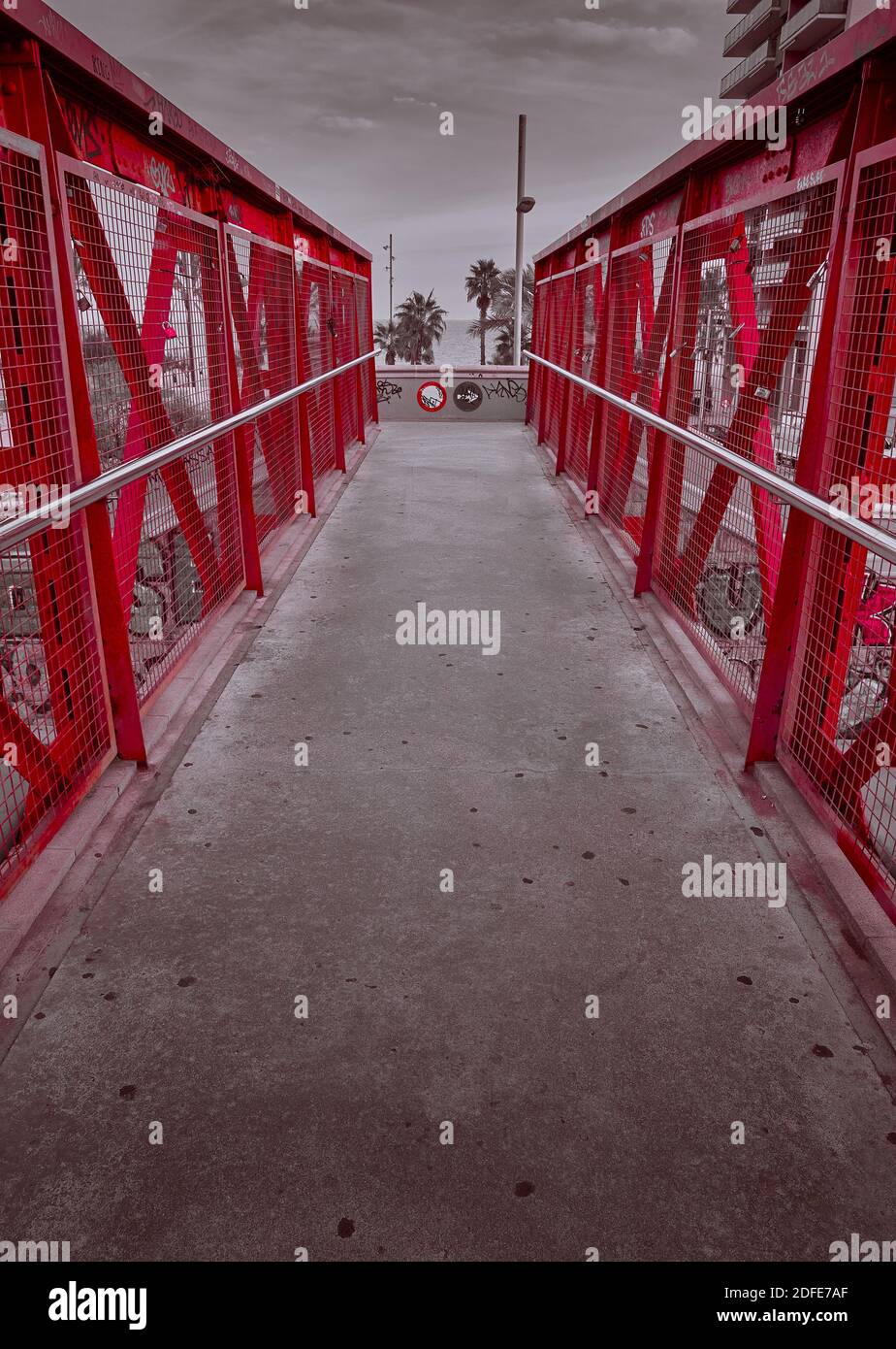 Prospettiva di un singolo ponte in metallo di colore rosso con palme sullo sfondo Foto Stock