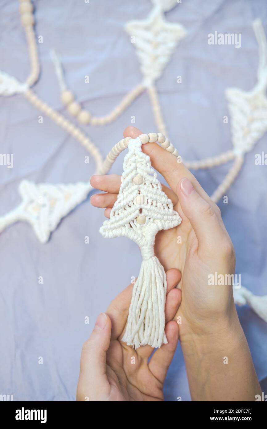 Crochet artigianale nuovo anno decorazione in mani donna. La persona tiene una ghirlanda di natale a forma di abete. Decorazione casa per le vacanze invernali co Foto Stock