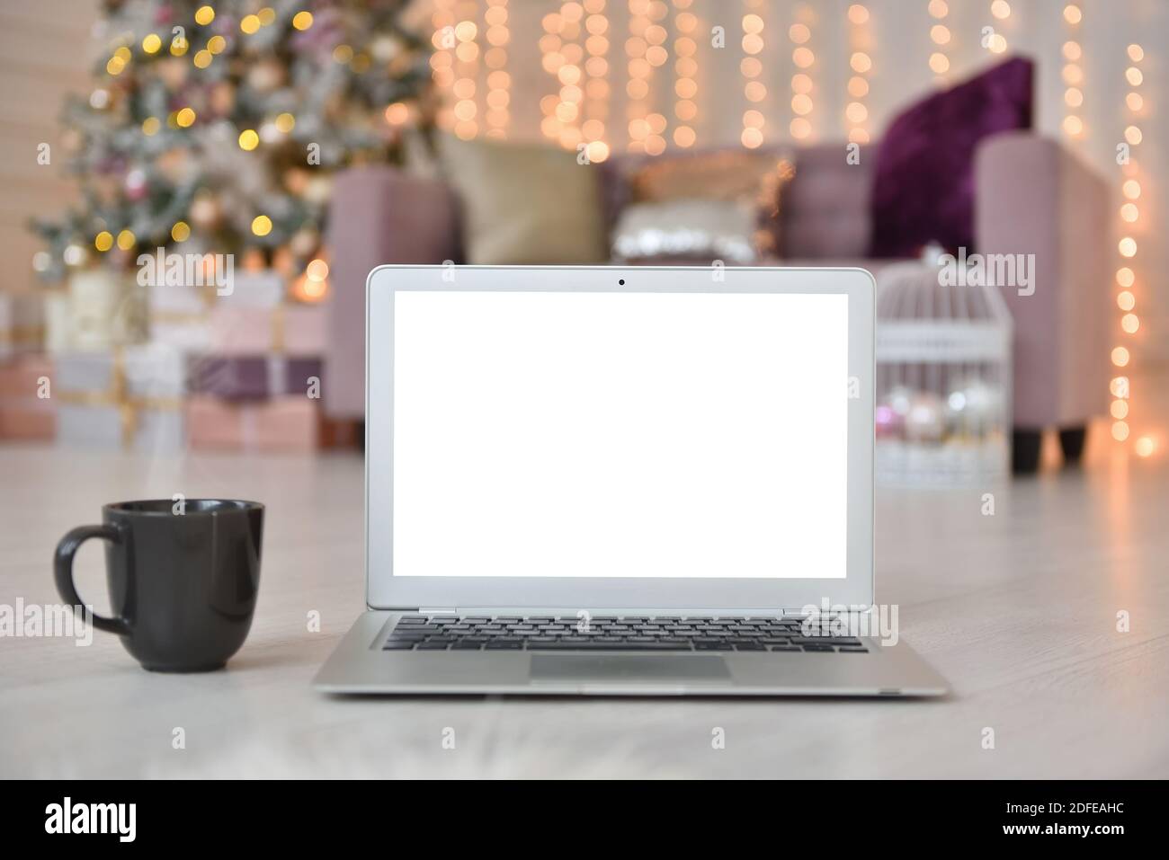 Computer portatile con schermo bianco vuoto sullo sfondo di Interni natalizi Foto Stock