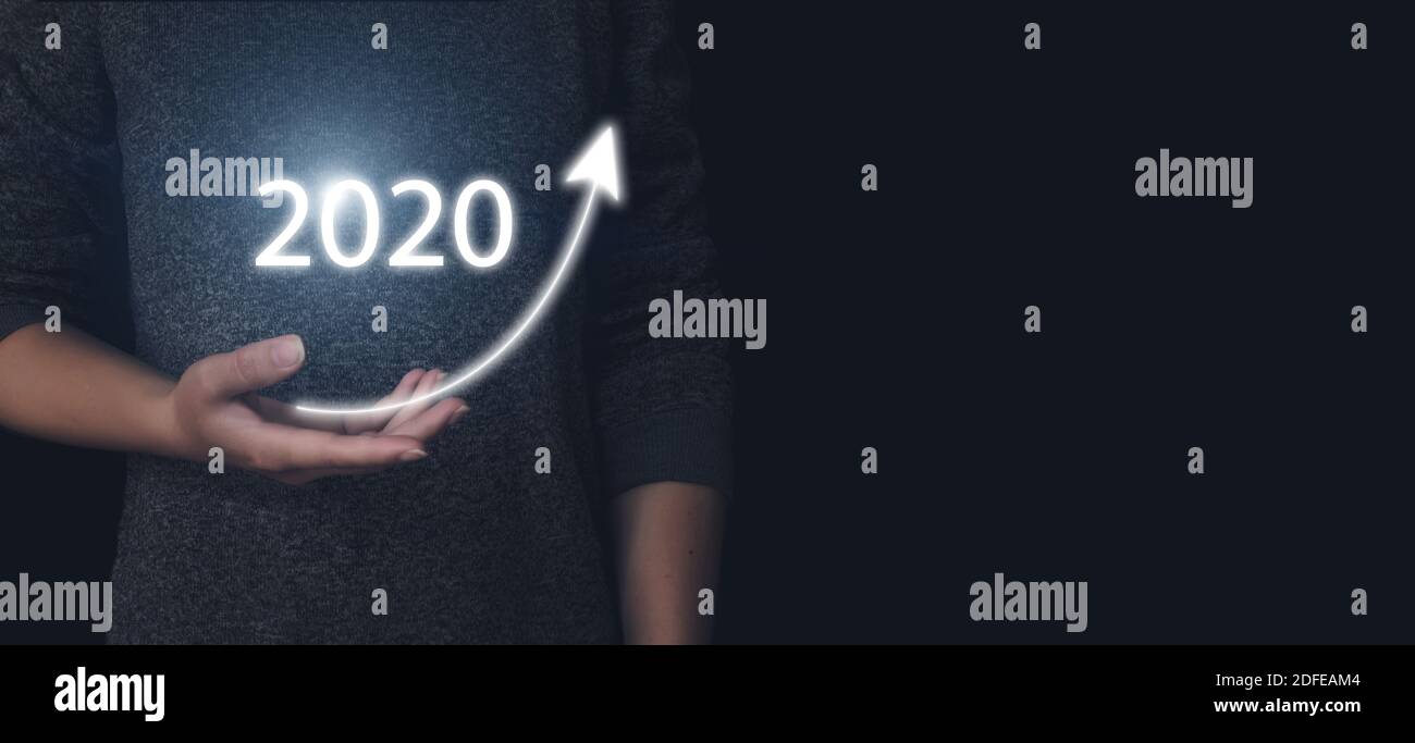 Mano che tiene una freccia in aumento con il gologramma 2020 anni. Il personale aziendale intende aumentare la crescita aziendale e aggiungere una crescita chiave nel 2020 Foto Stock