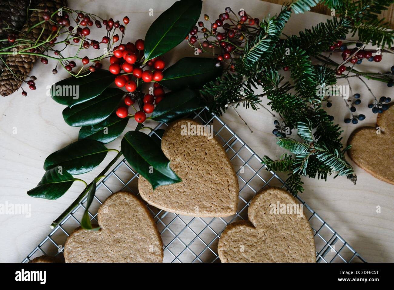 Disposizione di oggetti e decorazioni per le vacanze -- abete rosso verde, bacche rosse, zenzero cuore biscotti. Foto Stock