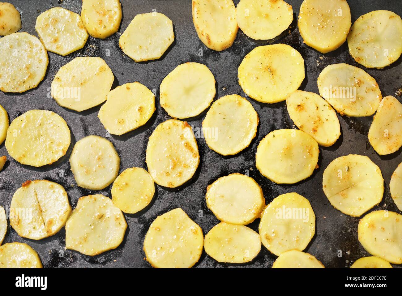 Patate tagliate a fette sottili, condite con spezie, grigliate su griglia elettrica, vista dall'alto Foto Stock