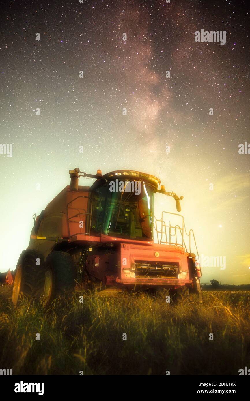Una mietitrebbia rossa si trova sotto la galassia della Via latte in una serata di primo autunno. Al dispositivo non è collegata alcuna testa. Foto Stock