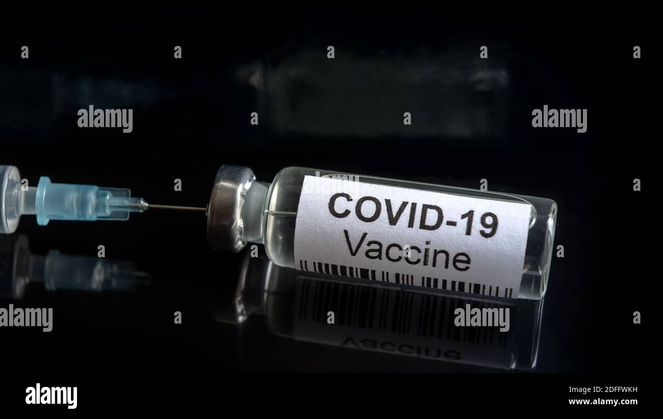Vaccino del coronavirus su close-up nero, siringa e flacone con vaccino per la cura COVID-19. Concetto di farmaco virus corona, trattamento, iniezione, medico Foto Stock