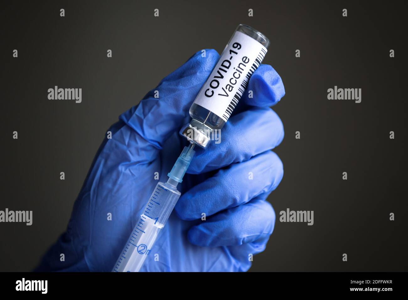 Flacone e siringa di vaccino del coronavirus per la cura con COVID-19 in primo piano con le mani chiuse del medico. Concetto di trattamento del virus corona, iniezione di vaccino, farmaco Foto Stock