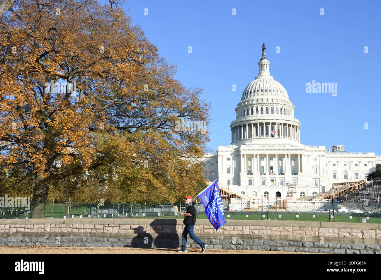 Washington DC. 14 novembre 2020. Milioni di Maga marzo. Un uomo con cappello rosso che cammina con la bandiera Trump 2020 di fronte al Campidoglio degli Stati Uniti. Foto Stock