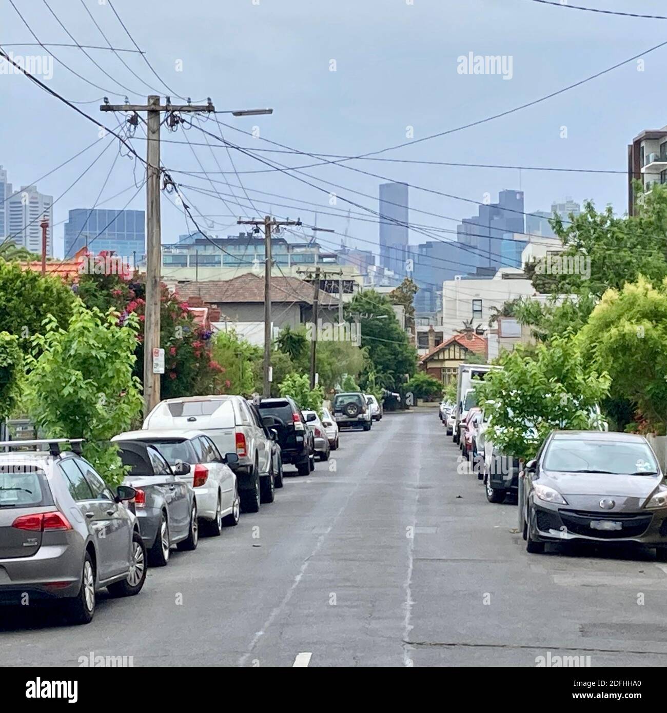 Strada secondaria suburbana con architettura vittoriana e auto parcheggiate in Melbourne, sobborgo interno di Richmond, con gli edifici del CBD della città sullo sfondo Foto Stock