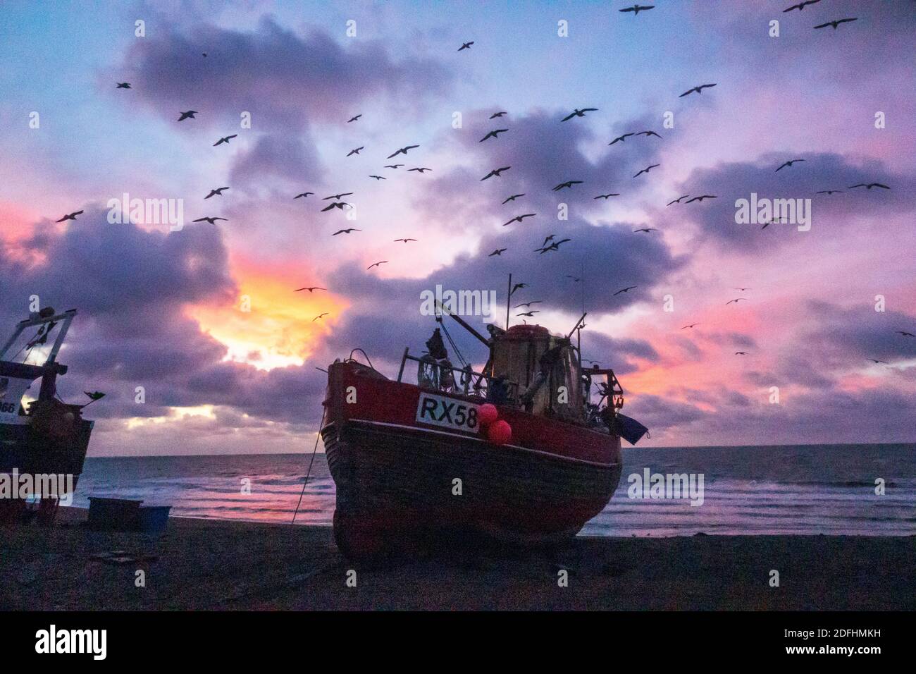 Hastings, East Sussex, Regno Unito. 5 dicembre 2020. I gabbiani girano all'alba sui pescherecci Hastings con un'alba colorata sulla Manica, il giorno dei colloqui di Boris Johnson con il presidente della Commissione europea Ursula von der Leyen, Cercare di sbloccare i diritti di pesca nelle acque britanniche e garantire un accordo commerciale all'ultimo minuto. Carolyn Clarke/Alamy Live News. Alba invernale Foto Stock