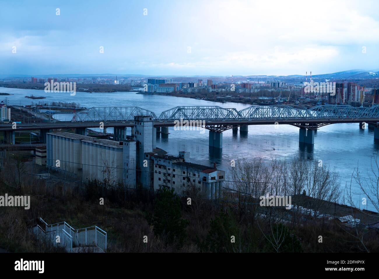 Ponte ferroviario sul fiume di una città densamente popolata. Foto Stock