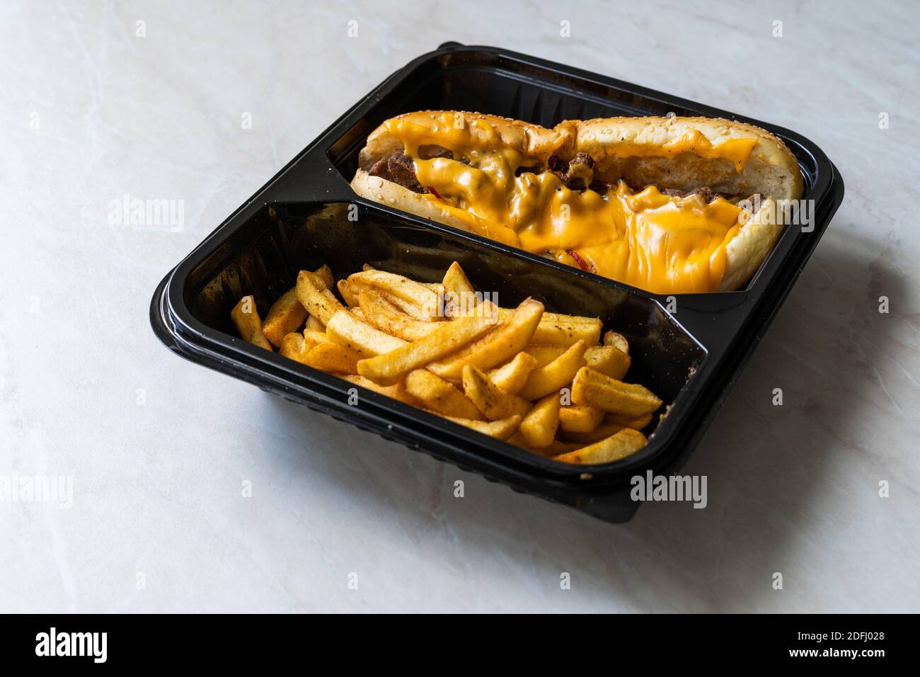 Take away Philly Cheese Steak Sandwich with fused Cheddar Cheese and Potatoes in Plastic Container Plate Package. Pronto a mangiare Foto Stock