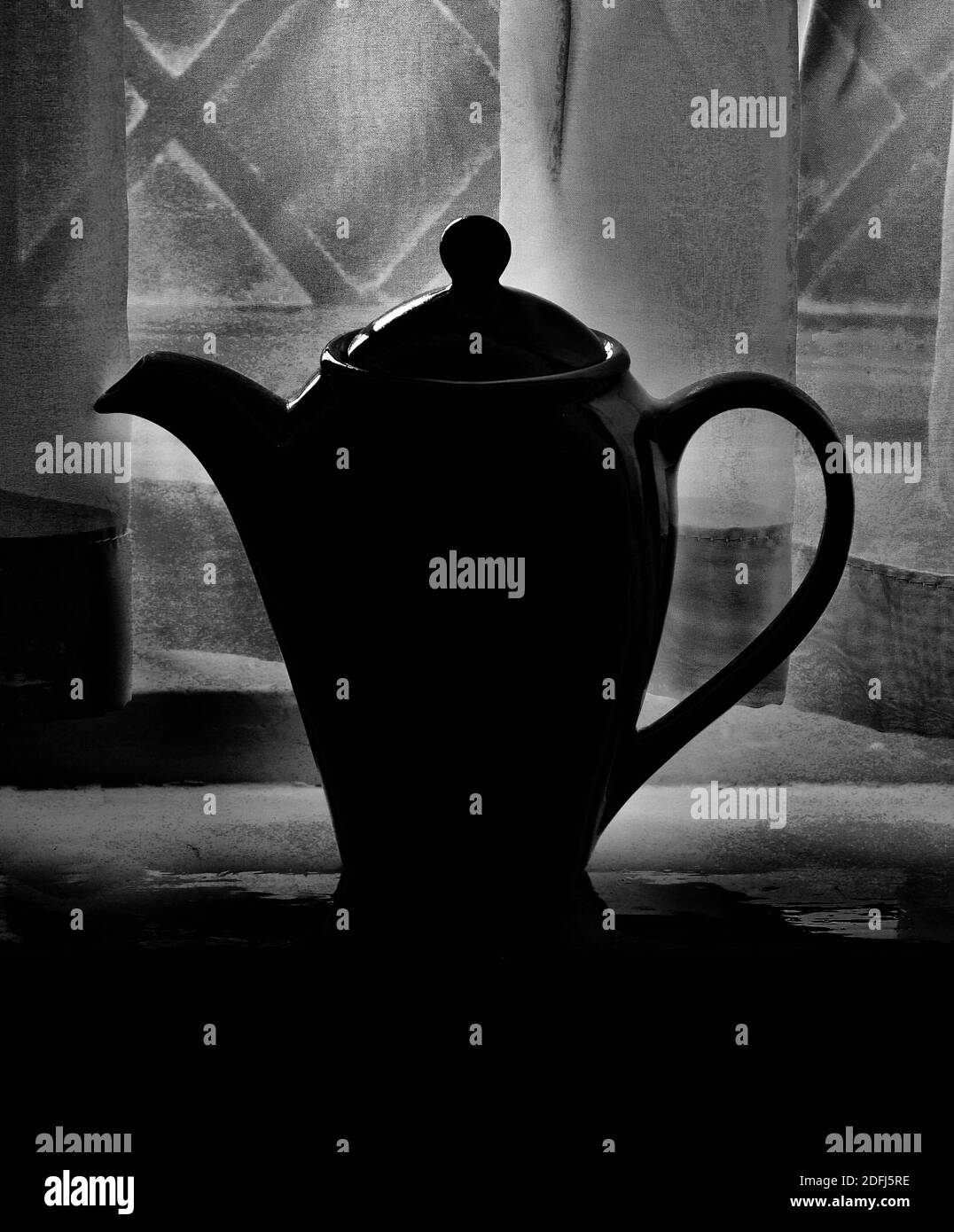 Immagine verticale in bianco e nero della caffettiera contro le tende Foto Stock