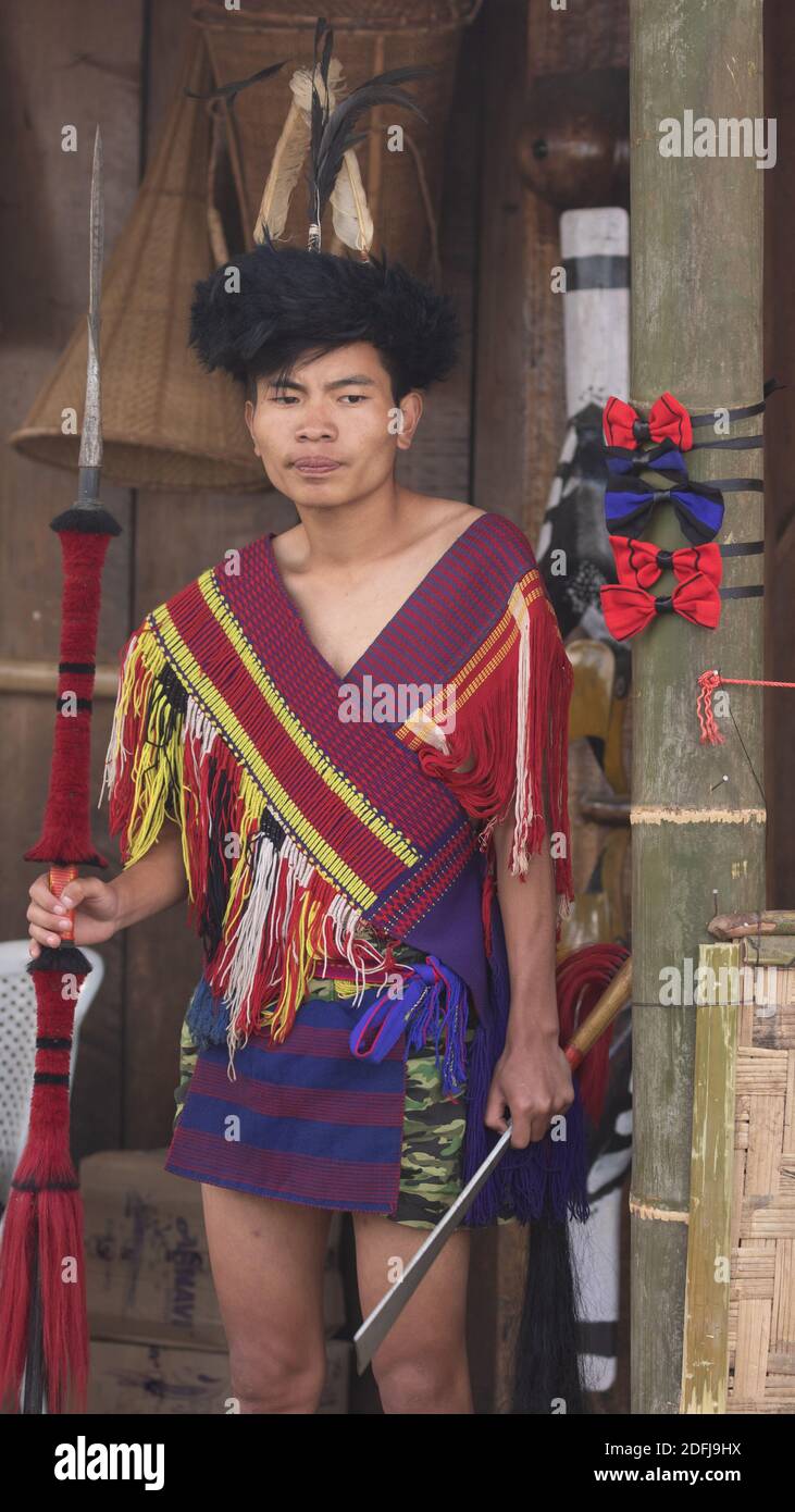 Un tribseman giovane Naga vestito in abito tradizionale con tradizionale Armi a Kohima Nagaland India il 4 dicembre 2016 Foto Stock