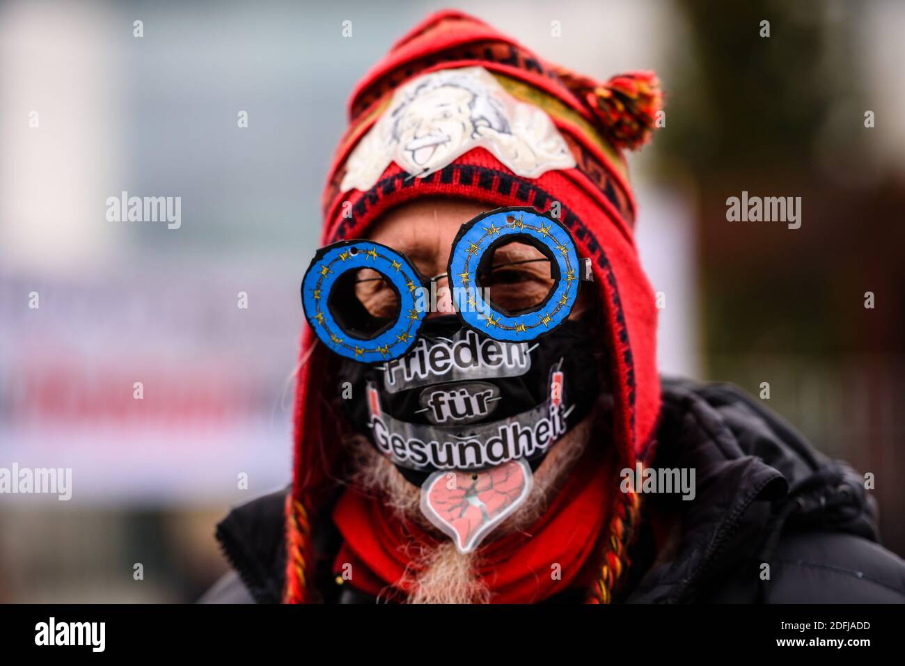 Germania, Berlino, 05 dicembre 2020: Un dimostratore che indossa una maschera quotidiana con la scritta "Pace per la Salute" mentre gli attivisti della pace manifestano di fronte alla Cancelleria federale per protestare contro l'aumento della spesa per armi nel contesto delle prossime discussioni sul bilancio nel Bundestag tedesco della prossima settimana. Gli organizzatori dell'iniziativa di pace 'disarmo anziché riarmo' (in tedesco: Abruesten statt Aufruesten) chiedono durante la Giornata nazionale 'disarmo e una nuova politica di detente' per un taglio delle esportazioni tedesche di armi e un cambiamento di politica sociale e ambientale. (Foto di Jan Scheunert/Sipa US Foto Stock