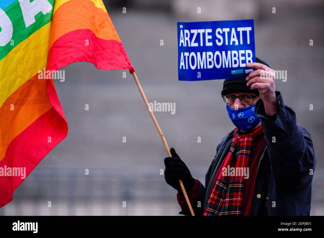 Berlino, Berlino, Germania. 5 dicembre 2020. Un dimostratore ha un cartello con la scritta "i detettori anziché i bombardamenti nucleari", mentre gli attivisti della pace si manifestano di fronte all'edificio tedesco del Reichstag per protestare contro l'aumento della spesa per le armi nel contesto delle prossime discussioni sul bilancio nel Bundestag tedesco della prossima settimana. Gli organizzatori dell'iniziativa di pace 'disarmo anziché riarmo' (in tedesco: Abruesten statt Aufruesten) chiedono durante la Giornata nazionale 'disarmo e una nuova politica di detente' per un taglio delle esportazioni tedesche di armi e un cambiamento di politica sociale e ambientale. (Credito im Foto Stock