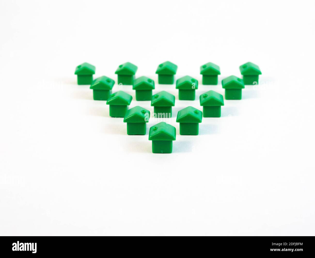 Pedine di colore verde a forma di casa con monete d'oro. Concetto intorno agli agenti immobiliari e immobiliari. Foto Stock