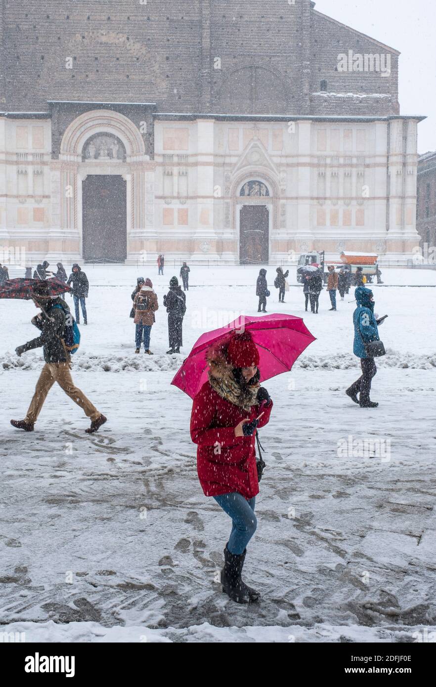 Inverno a Bologna, Italia. Neve che cade in Piazza maggiore presso la Basilica di San Petronio, durante la "bestia da Oriente". Donna sotto l'ombrello rosa. Foto Stock