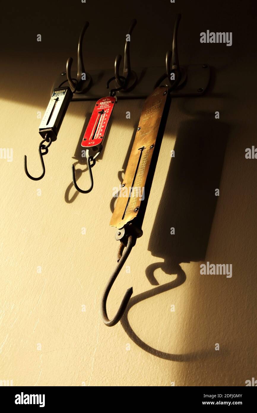 Tre bilance a molla per la misurazione dei pesi degli articoli appesi ai ganci. Foto Stock Tre bilance a molla per la misurazione dei pesi degli articoli appesi ai ganci. Foto Stock