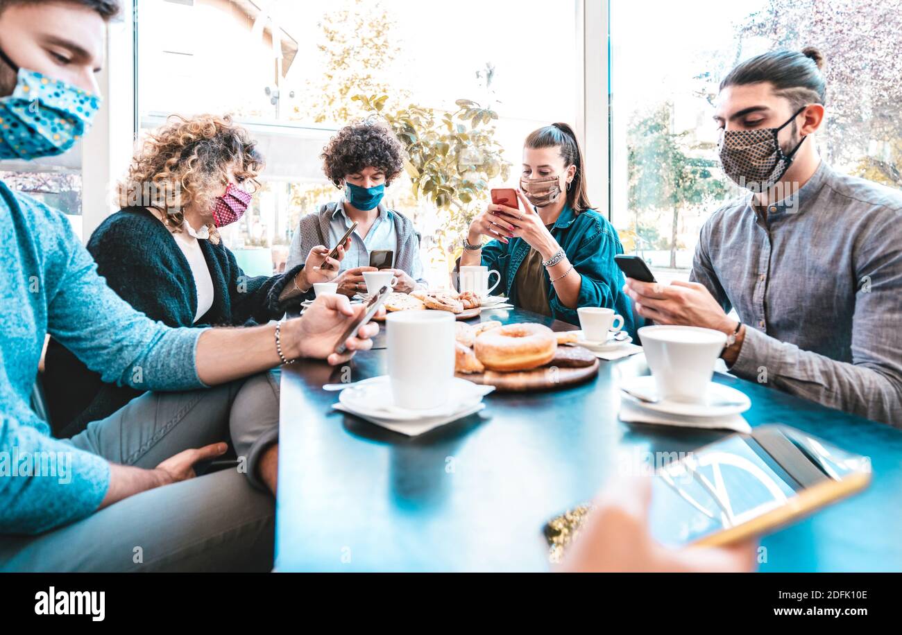 I dipendenti aziendali sono preoccupati di utilizzare smartphone mobili durante la pausa caffè - nuovo concetto di stile di vita normale con le persone che indossano maschere per il viso Foto Stock