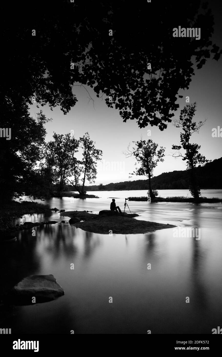 Un fotografo si siede su un'isola di notte e fotografa la natura. Foto Stock