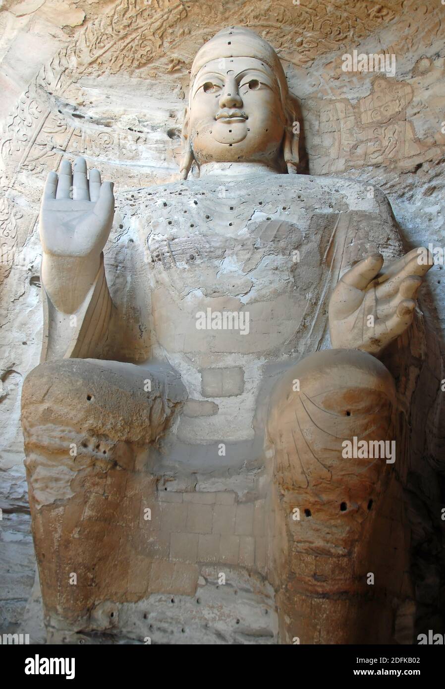 Grotte di Yungang vicino a Datong nella provincia di Shanxi, Cina. Grande statua antica di Buddha in una grotta a Yungang. Vista verticale dalla parte anteriore. Foto Stock