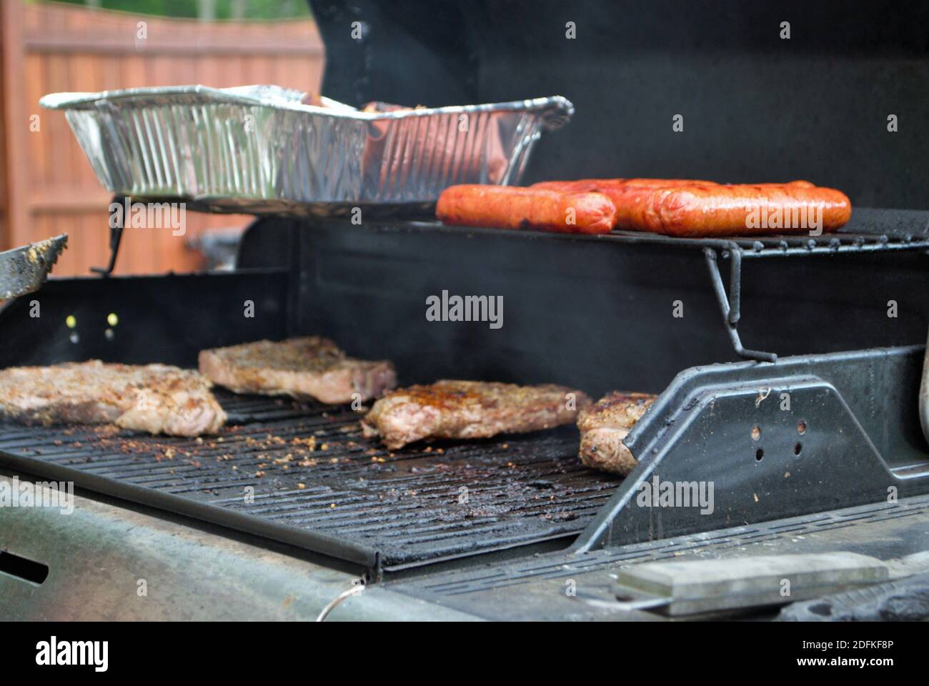 Hot dog e bistecca sulla griglia in un cortile di cucina Foto Stock