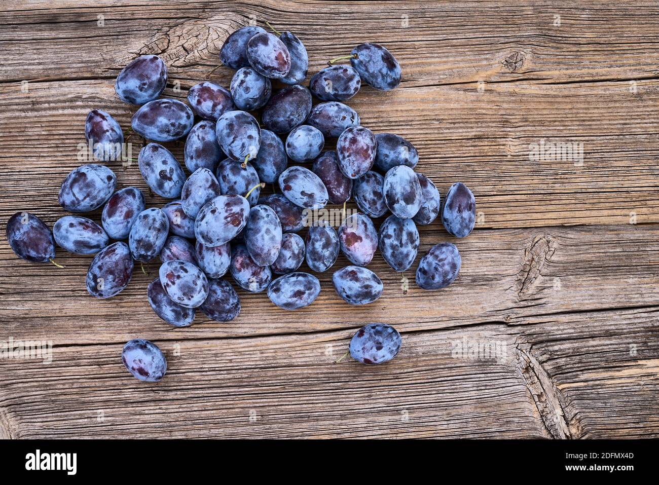 Prugne blu fresche su un vecchio tavolo di legno. Cibo biologico. Vista dall'alto, spazio di copia. Foto Stock