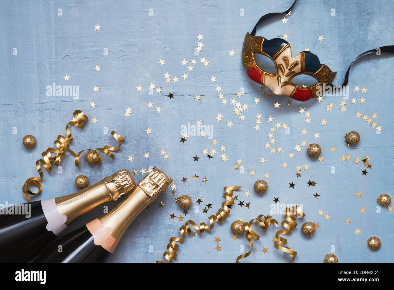 Due bottiglie di champagne con maschera di carnevale, stelle di confetti e balena di festa su sfondo blu. Piatto di Natale, anniversario, carnevale, New Yea Foto Stock