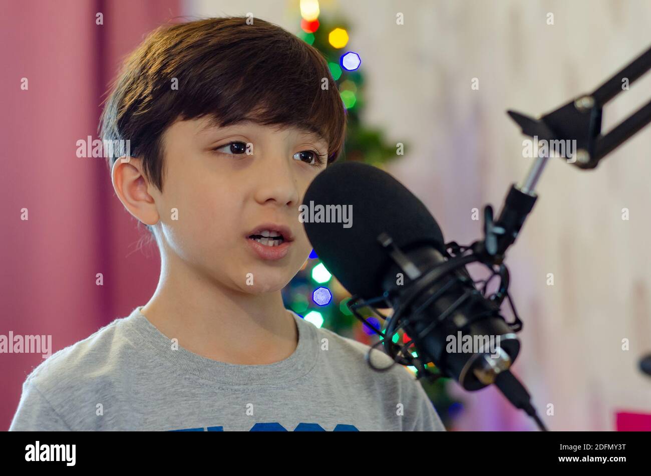 Un ragazzo che canta in un microfono, registrando voci per una canzone. Foto Stock