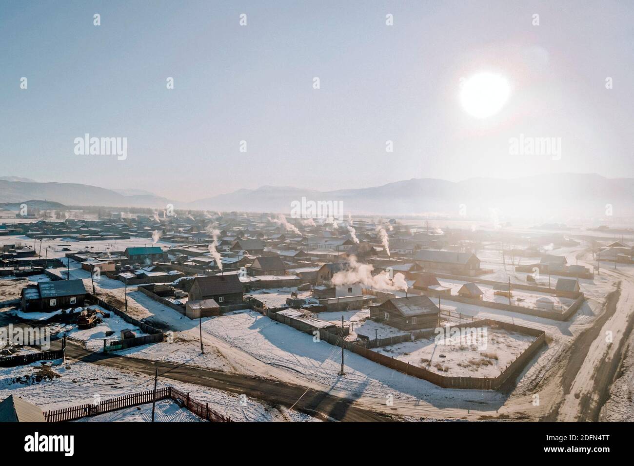 Villaggio in Siberia durante il giorno. La vista dall'alto. Molte case in legno in campagna con riscaldamento a stufa. Giorno gelido. Foto Stock
