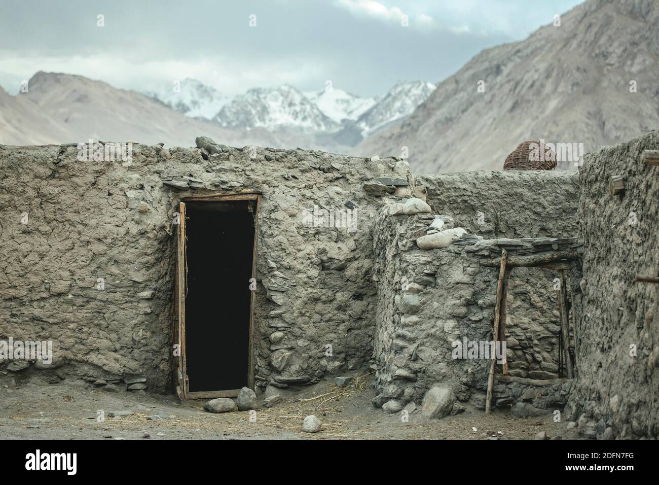Casa di argilla e mattoni, porta aperta, dietro di esso cima del Kush indù, corridoio di Wakhan, Saradh-e-Broghil, Afghanistan Foto Stock