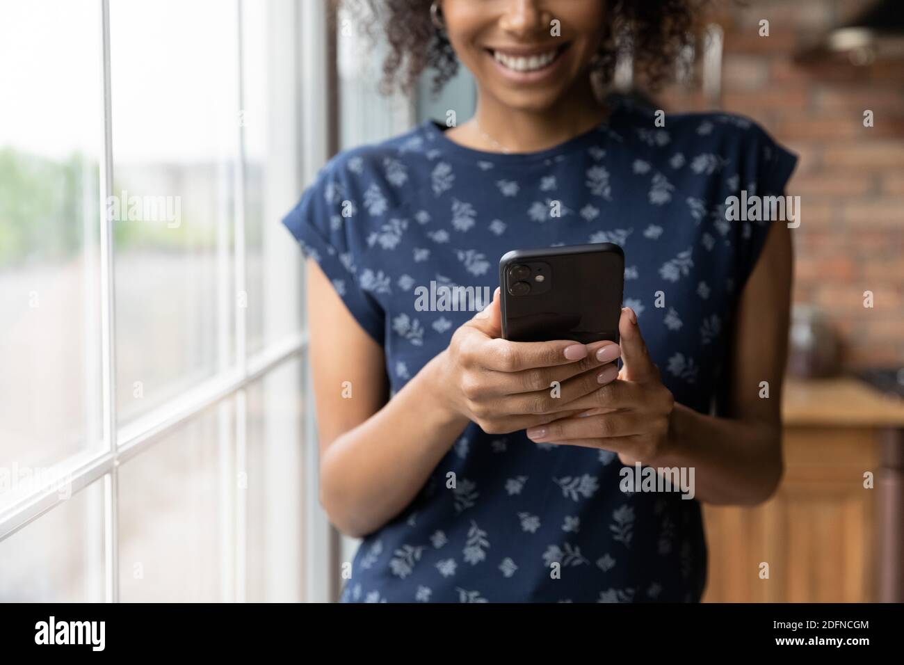 Primo piano felice multirazziale giovane donna utilizzando il telefono cellulare. Foto Stock
