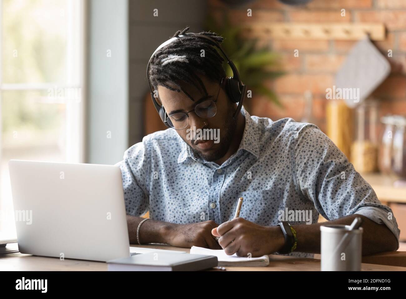 Concentrato 30s giovane ragazzo di razza mista che studia a casa. Foto Stock